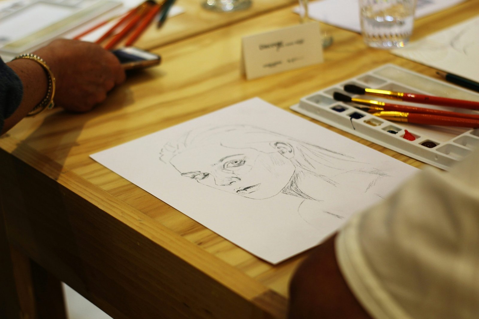 a person sitting at a table with a drawing of a woman